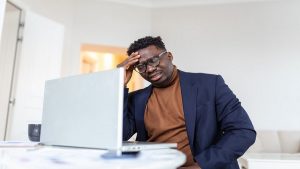 Skilled profession looking at his laptop and frustrated by unfair hiring practices